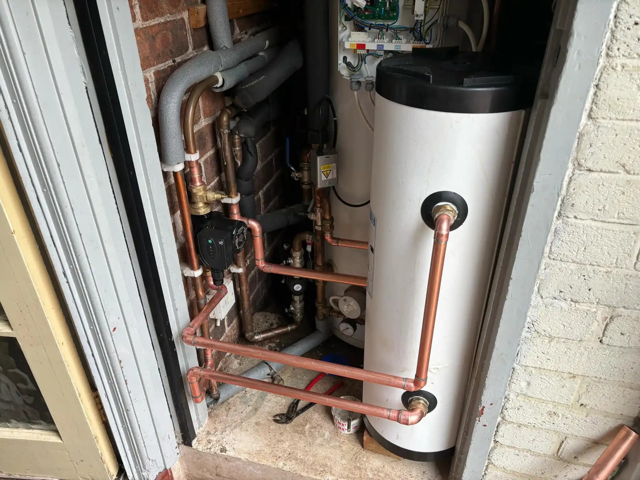 Hot water cylinder installation with copper pipework and heating components.