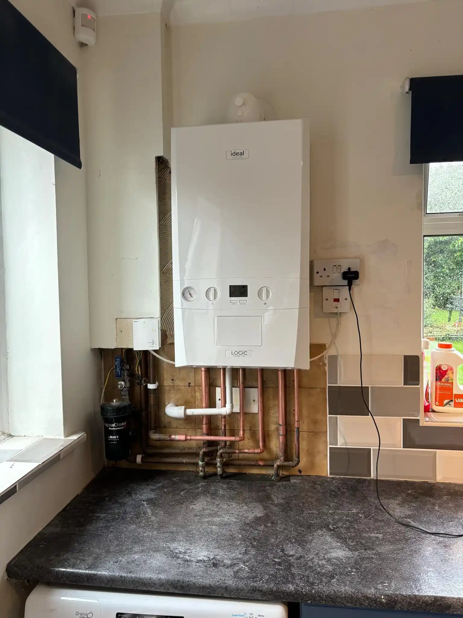 Combi boiler installation above a kitchen worktop with copper pipework.